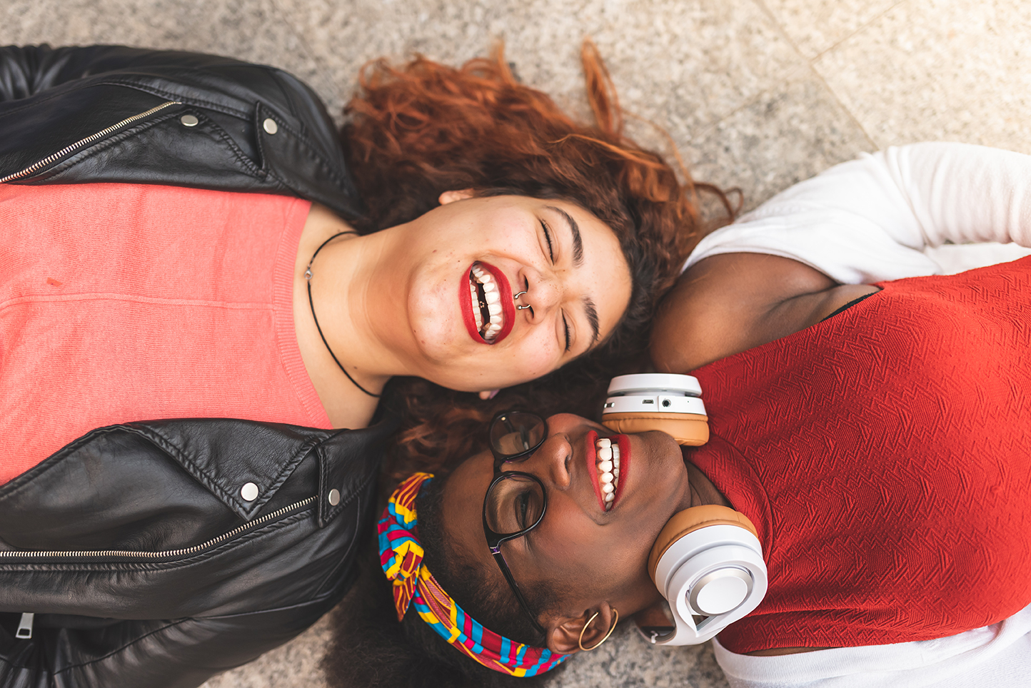 Two Teenage Girls Laying Down ; Looking Each Other and Smiling.